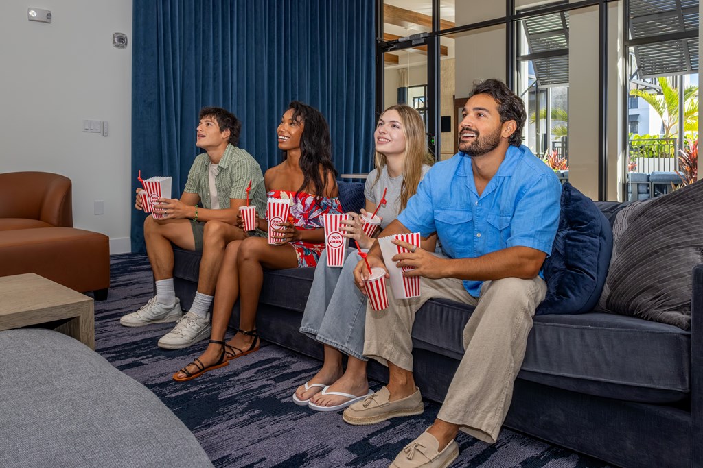 Four people sitting on a couch eating popcorn.