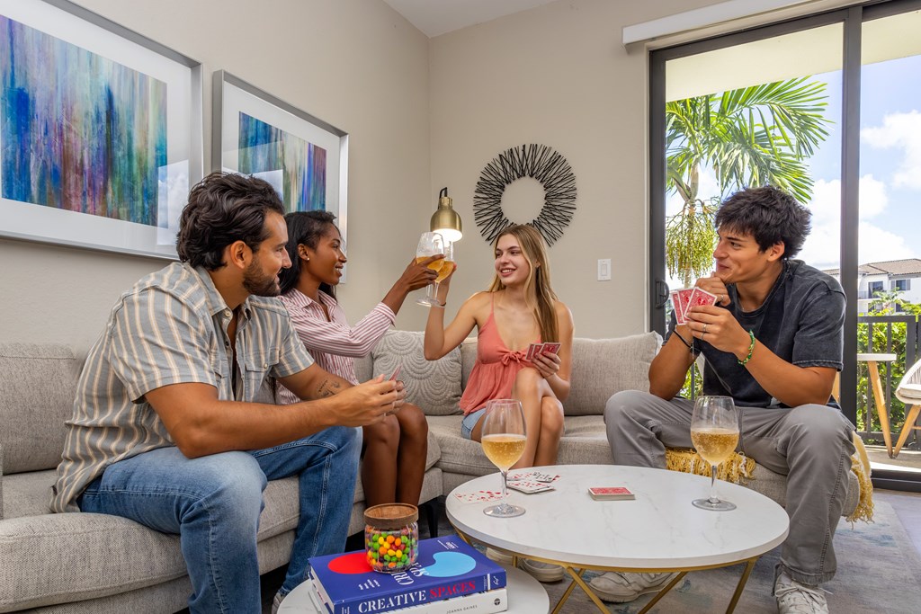 Four people are sitting on a couch and enjoying drinks together.