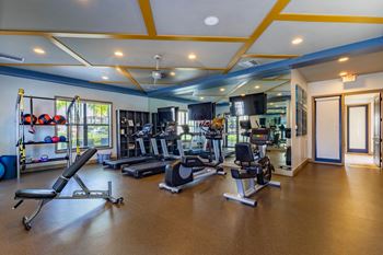 A gym with a variety of equipment including treadmills, weights, and exercise machines.
