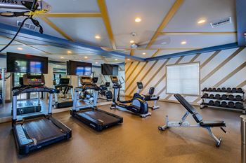 A gym with treadmills, exercise equipment, and a striped wall.
