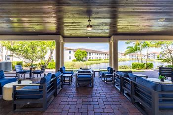 A patio with blue chairs and tables overlooking a body of water.
