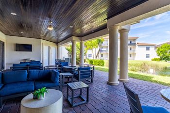 A patio with a blue couch and a table with a potted plant on it.