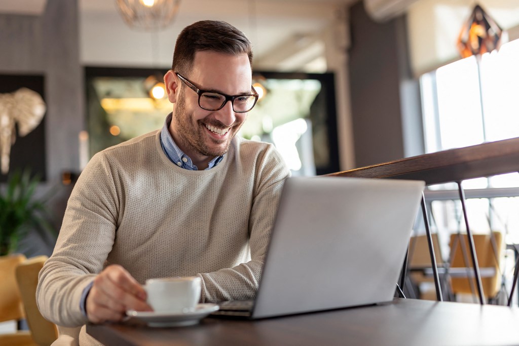 a man sitting at a table with a laptop computer at The Falls of Portofino, Naples, Florida