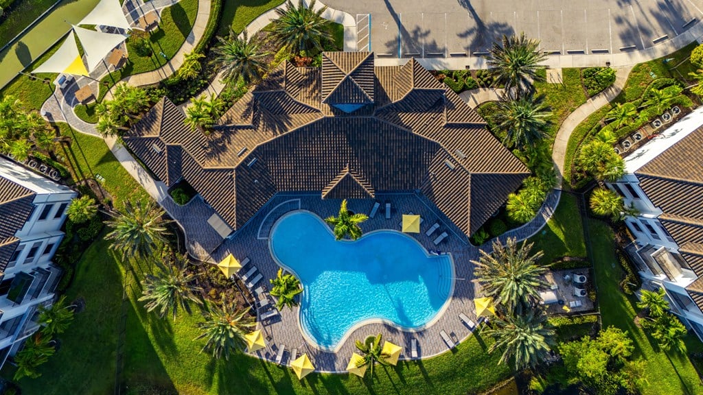 A large house with a pool in the middle of a grassy area.