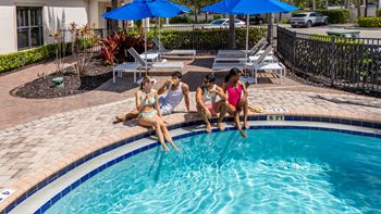 Three women sunbathing by a pool.