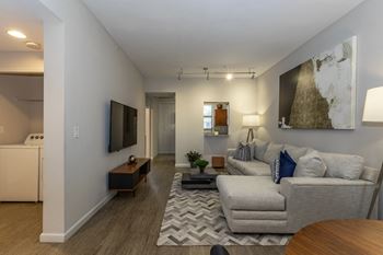 A living room with a grey couch and a television on the wall.