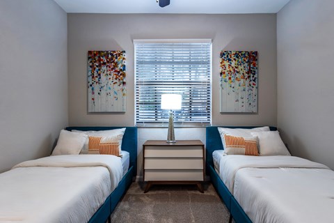 A bedroom with two beds and a nightstand.