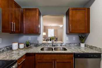 A kitchen with a granite countertop and wooden cabinets.