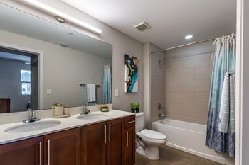 A bathroom with a white toilet, a sink with a mirror above it, and a shower area with a blue shower curtain.