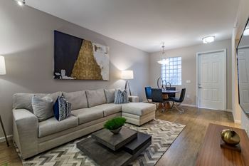 A living room with a grey couch, a coffee table, and a painting on the wall.