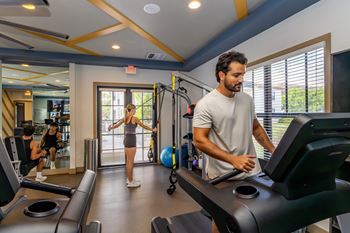 A man and a woman are working out on treadmills in a gym.