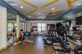 A gym with people working out and a mirror on the wall.