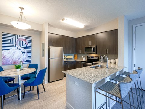 a kitchen with a large island with granite countertops and dark wood cabinets