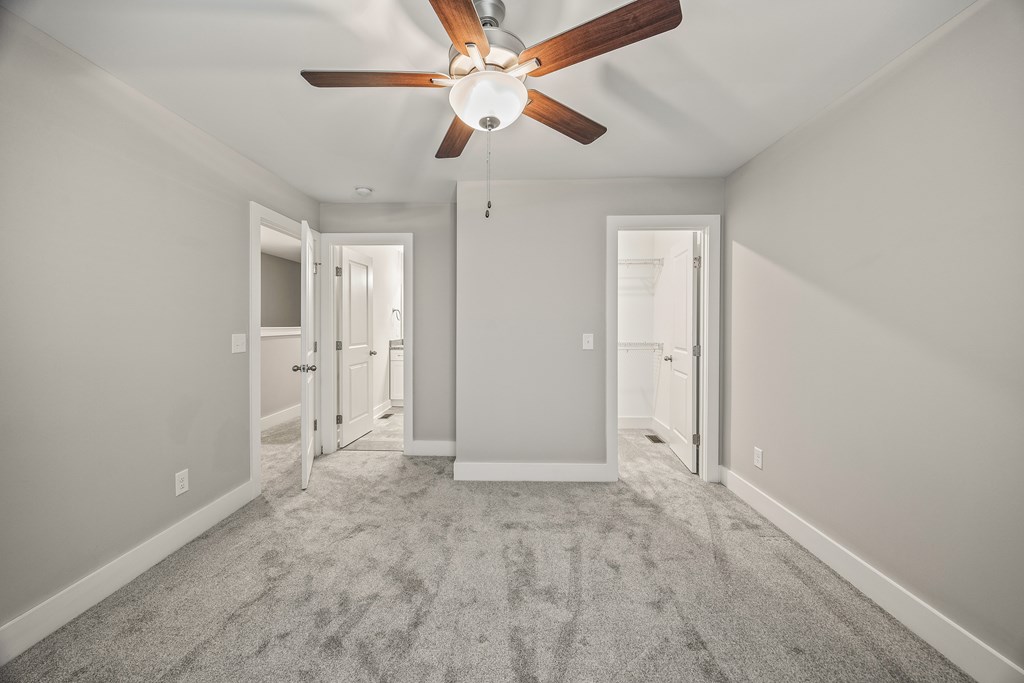 A spacious room with a ceiling fan and carpeted floor.