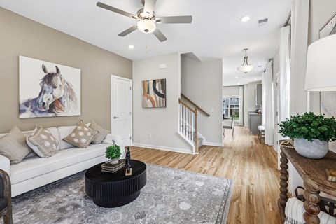 A living room with a white couch, a coffee table, and a painting of a horse on the wall.