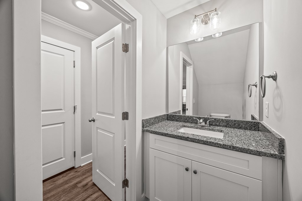 A bathroom with a sink, mirror, and two doors.