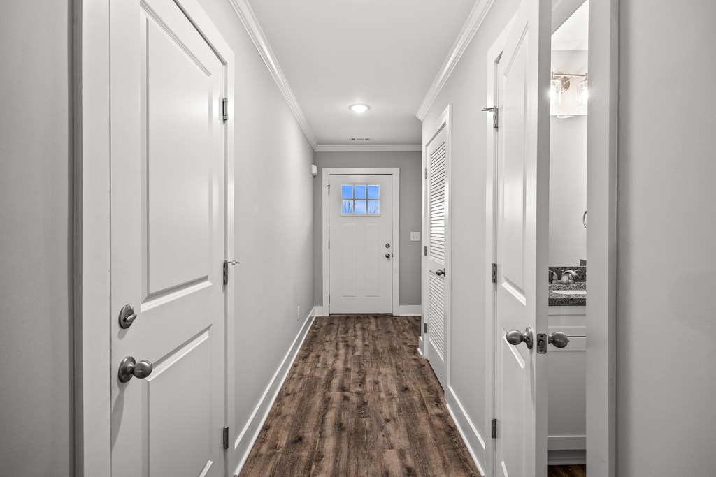 A long hallway with white doors and a wooden floor.