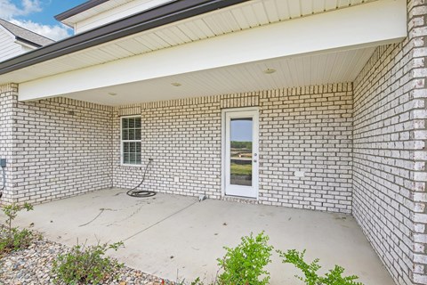 A white brick house with a small window and a door.
