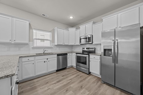 A modern kitchen with white cabinets and stainless steel appliances.