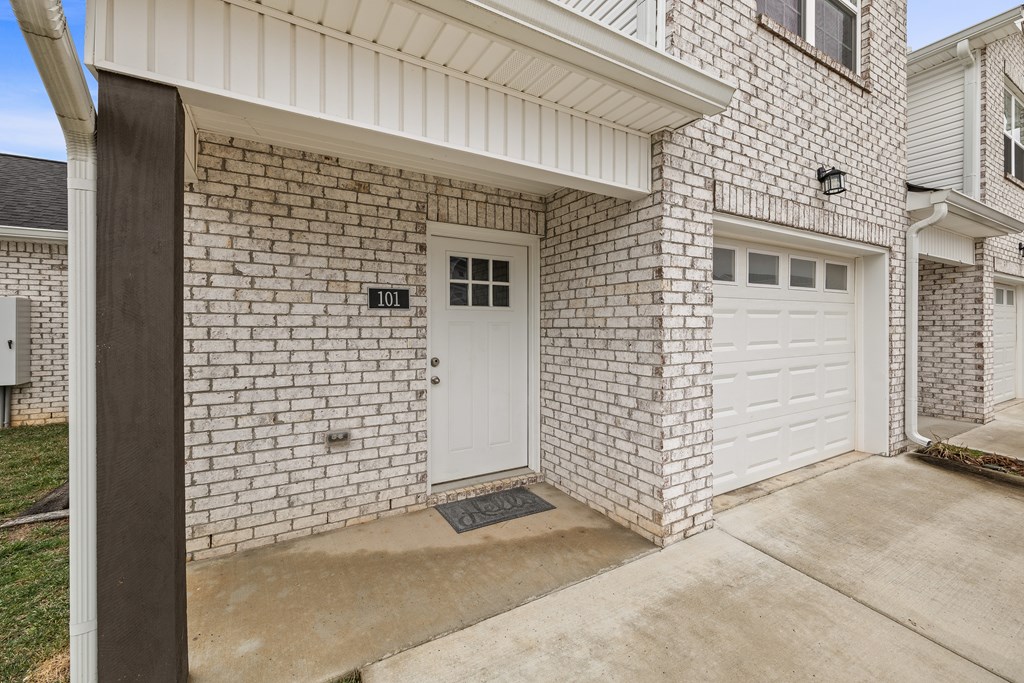 A white door with a number 101 on it is on a brick house.