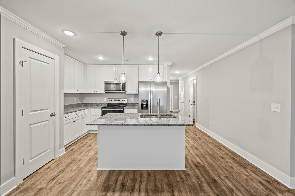 A kitchen with a white island and wooden floors.