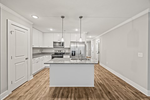 A kitchen with a white island and wooden floors.