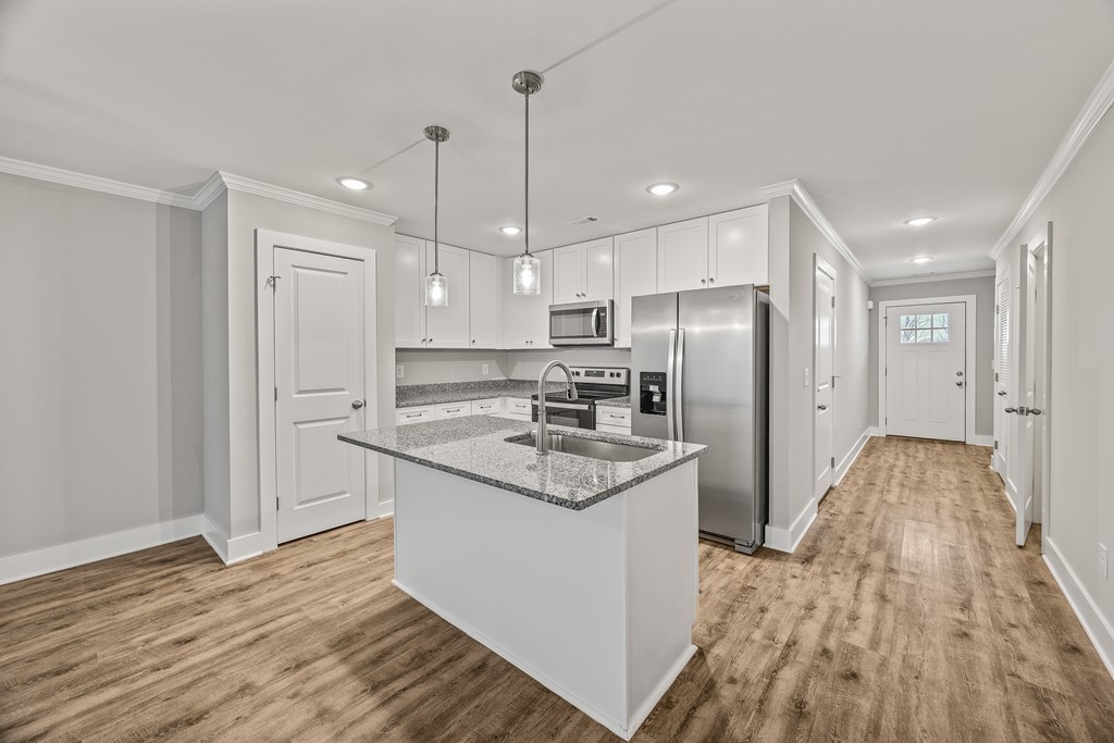 A kitchen with a center island and pendant lights.