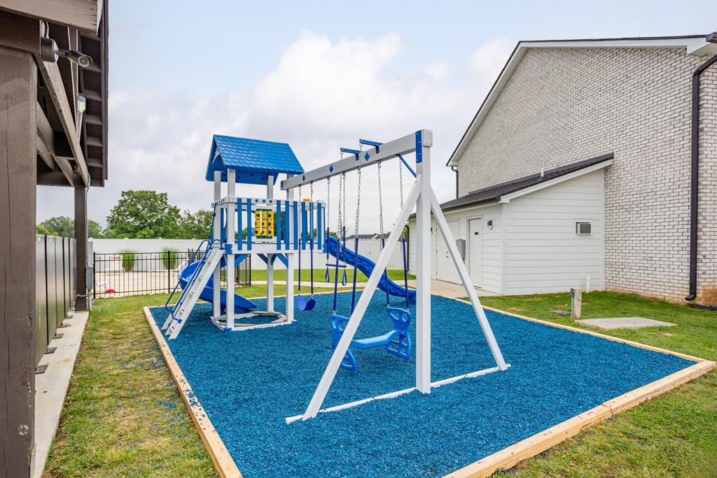 A playground with a blue slide and a white frame.