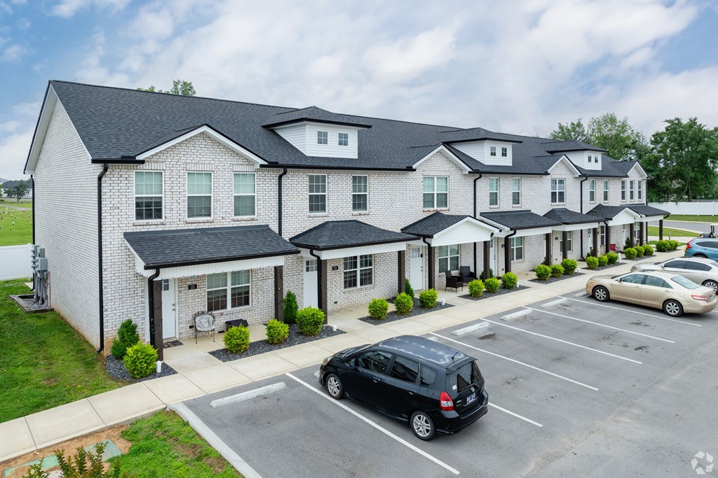 A white building with a black roof and a parking lot in front.