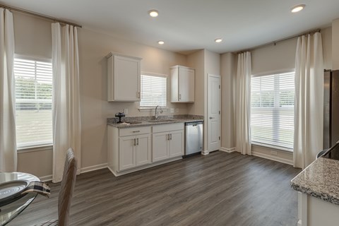 A kitchen with white cabinets and a wooden floor.