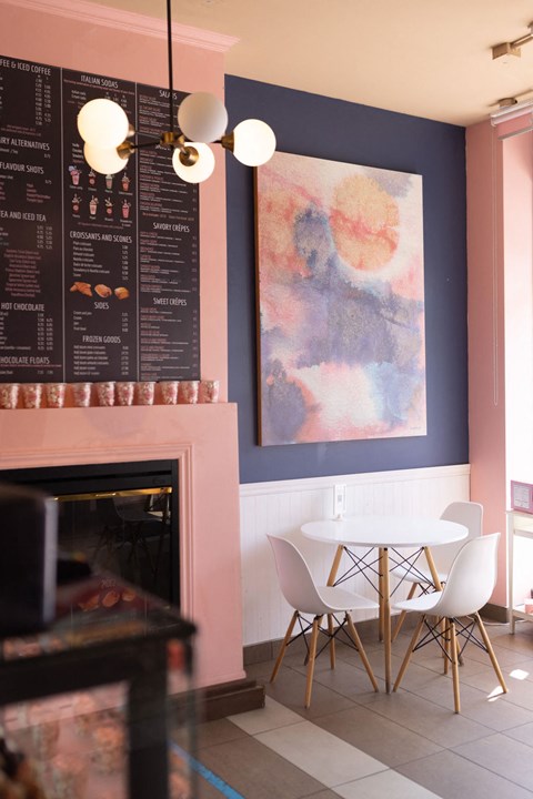 a dining room with a white table and chairs and a fireplace with a painting on the wall