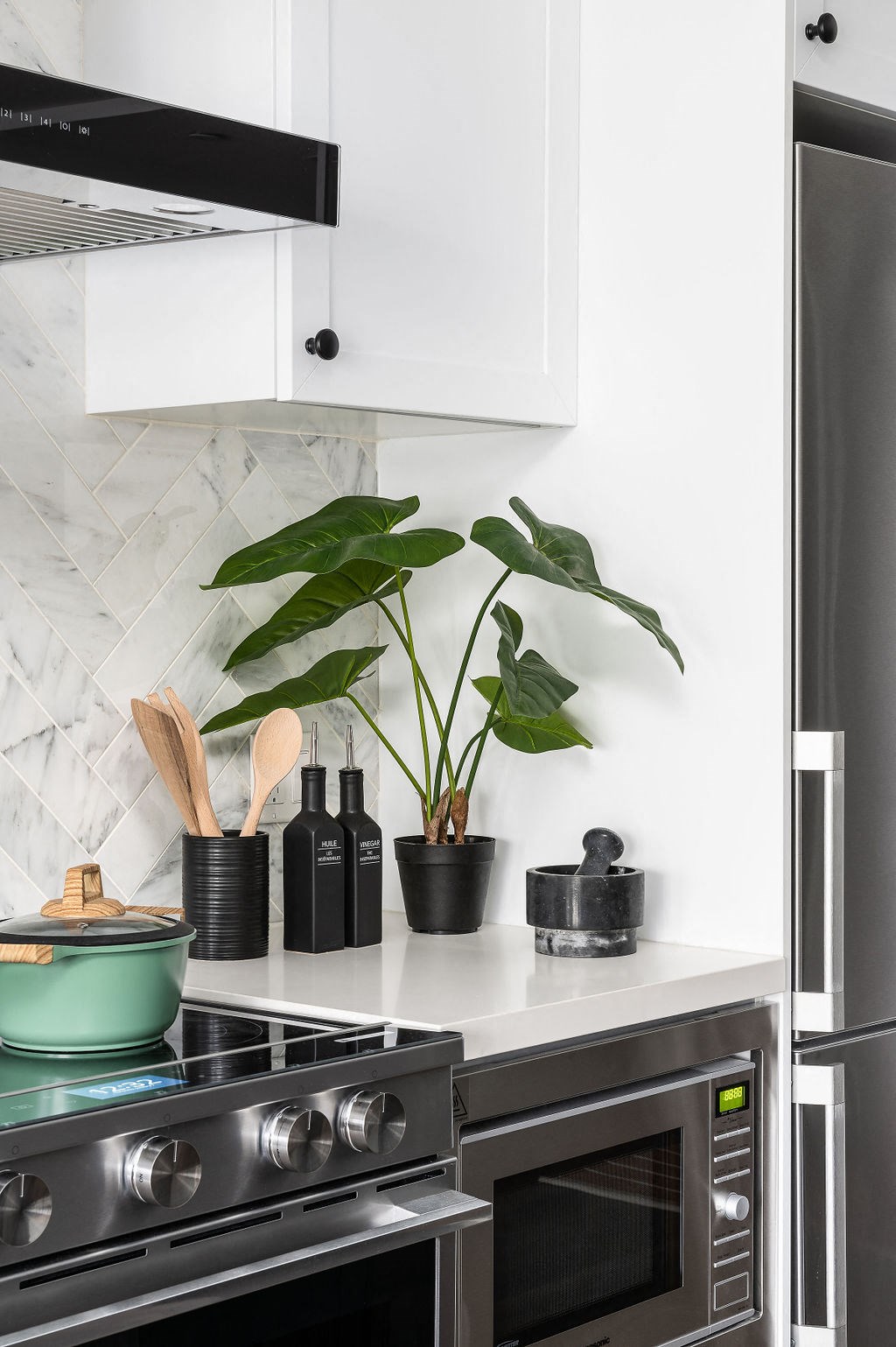 a kitchen with white cabinets and a stove and a plant