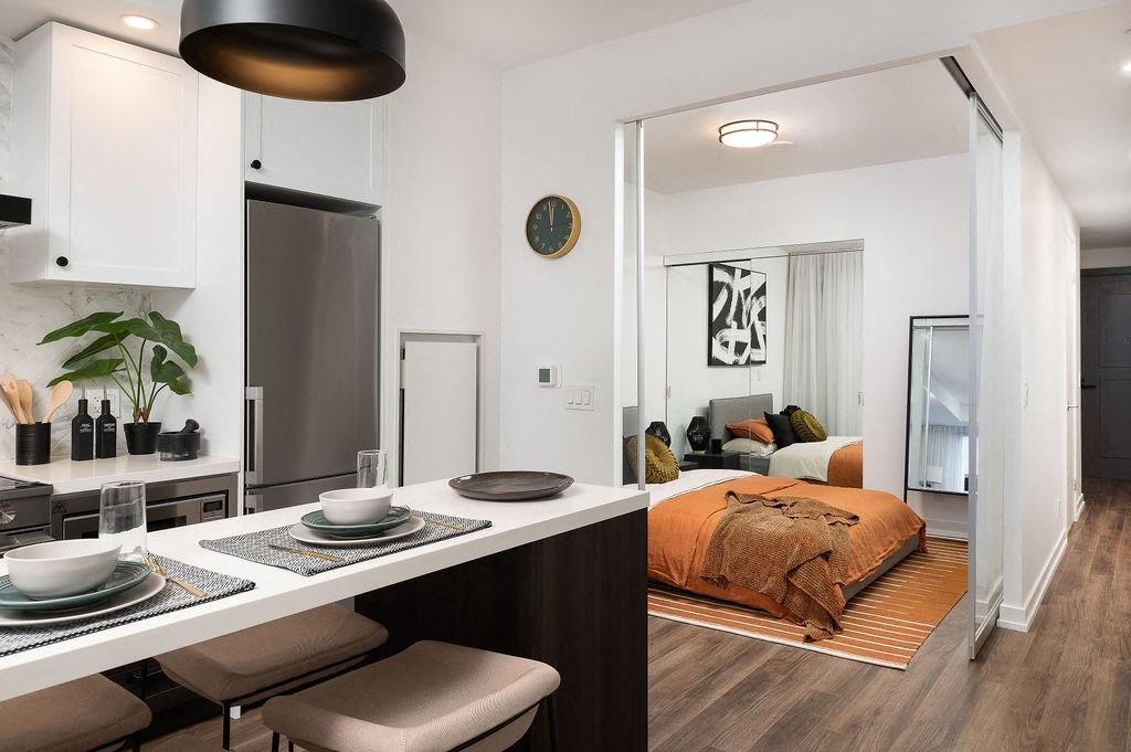 a bedroom with a bed and a kitchen in a room