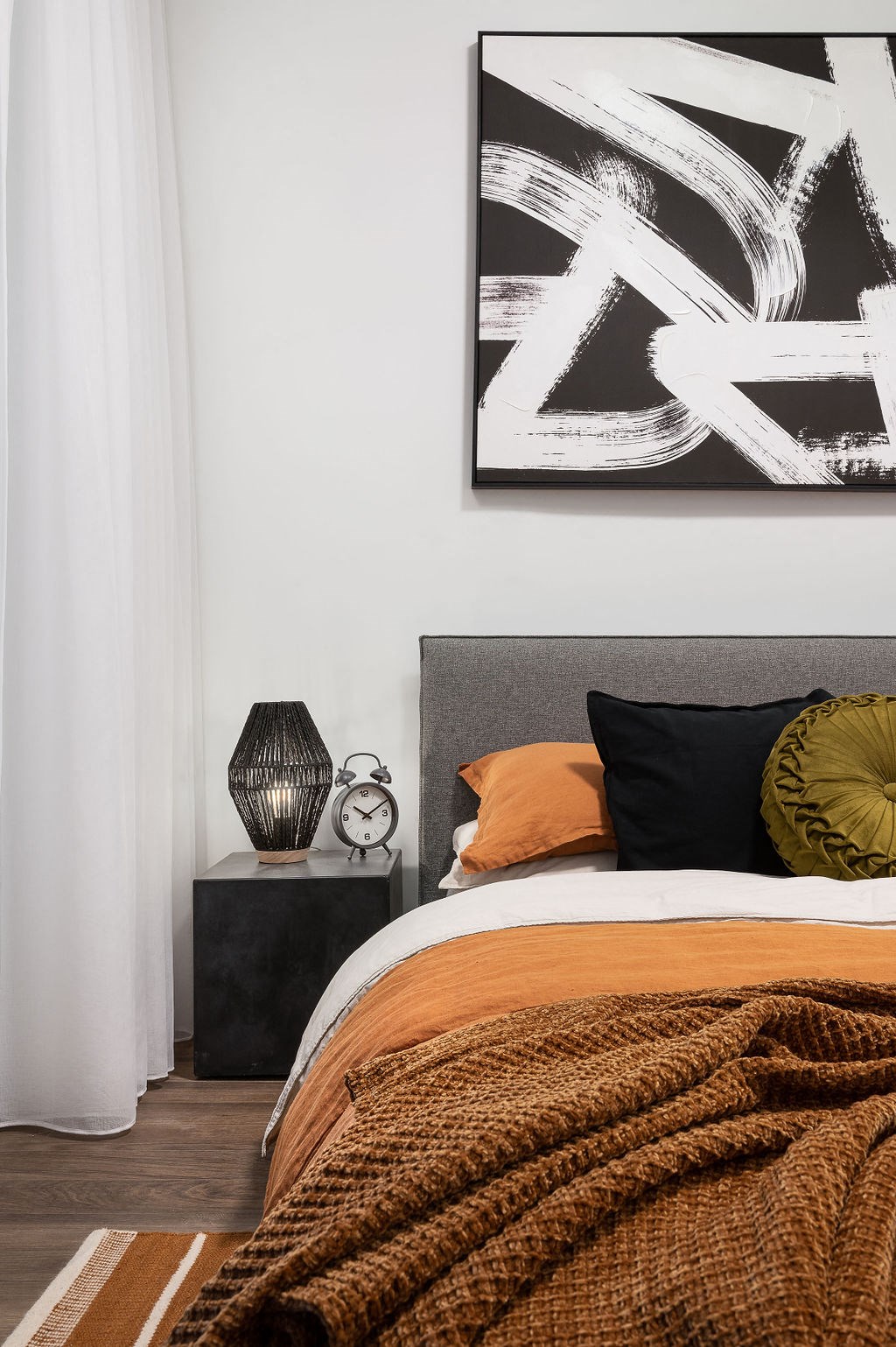 a bedroom with a bed and a black and white painting on the wall