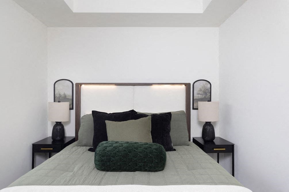 a white bedroom with a bed and a green pillow