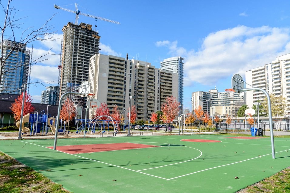 a basketball court in a city park with buildings in the background