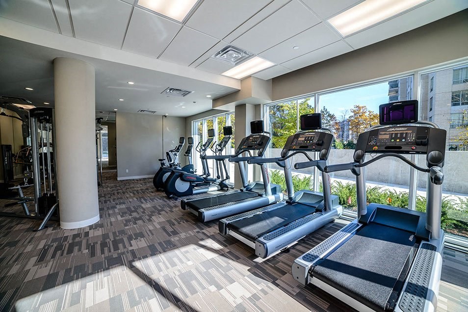 a gym with cardio equipment and windows in a building