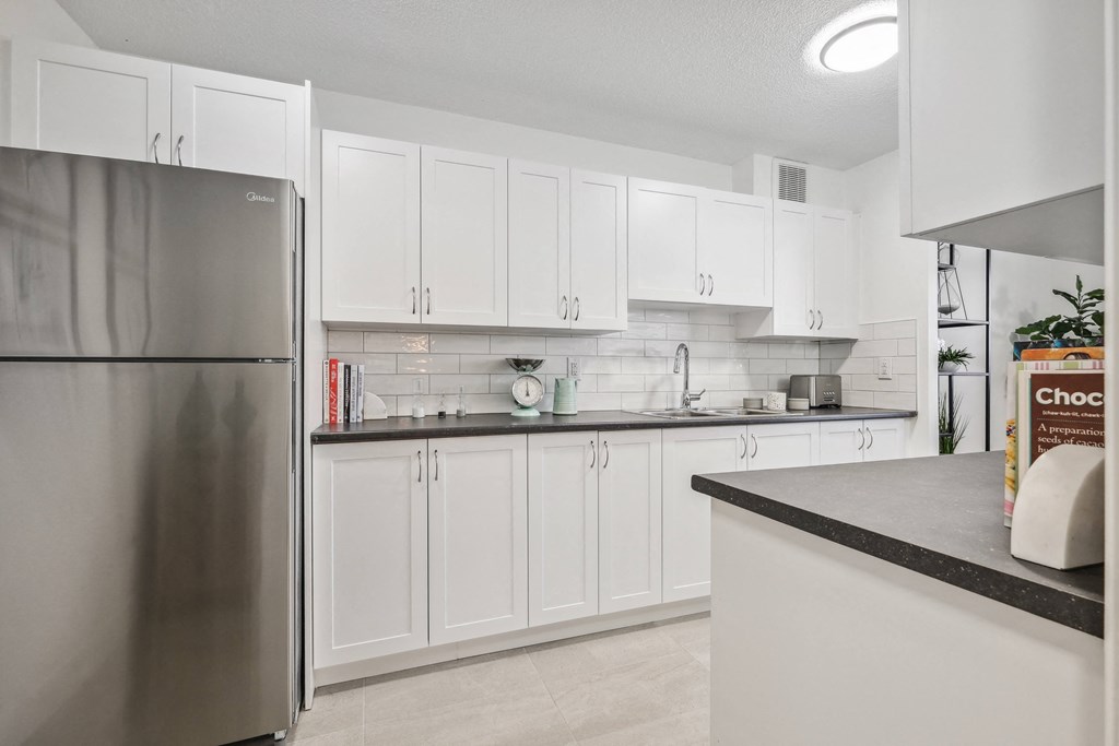 an open kitchen with white cabinets and a stainless steel refrigerator