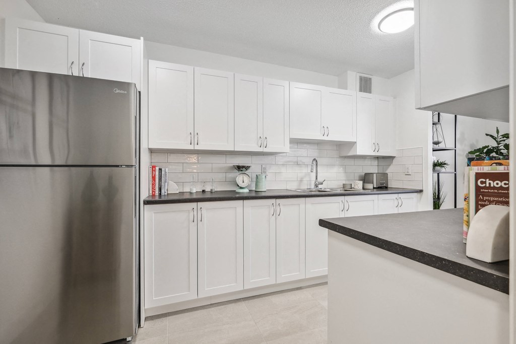 a large kitchen with white cabinets and a stainless steel refrigerator