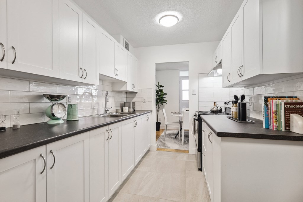 a white kitchen with white cabinets and black counter tops