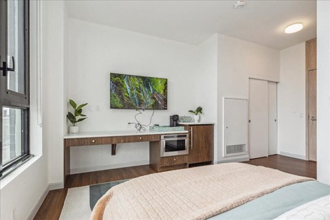 A bedroom with a bed, a wooden cabinet, and a painting on the wall.