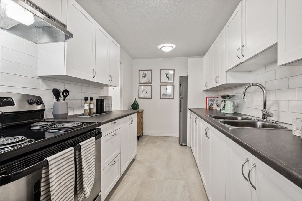 a kitchen with white cabinets and black counter tops and a sink