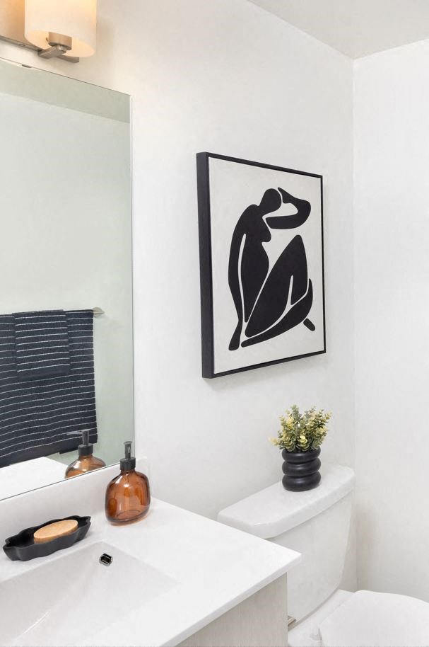a white bathroom with a picture of a woman on the wall