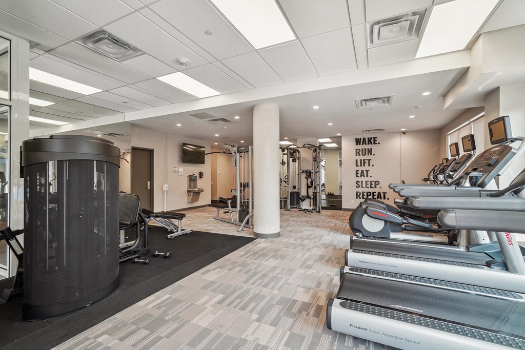 a gym with treadmills and other exercise equipment in a building with white ceilings