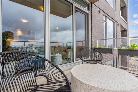 A balcony with a chair and table overlooking a pool.