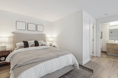 a white bedroom with a large bed and a bathroom