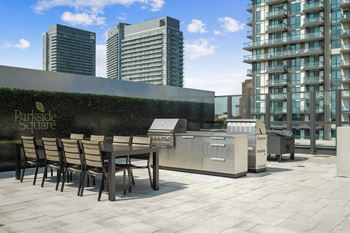 a communal terrace with a table and barbecue grill on a rooftop