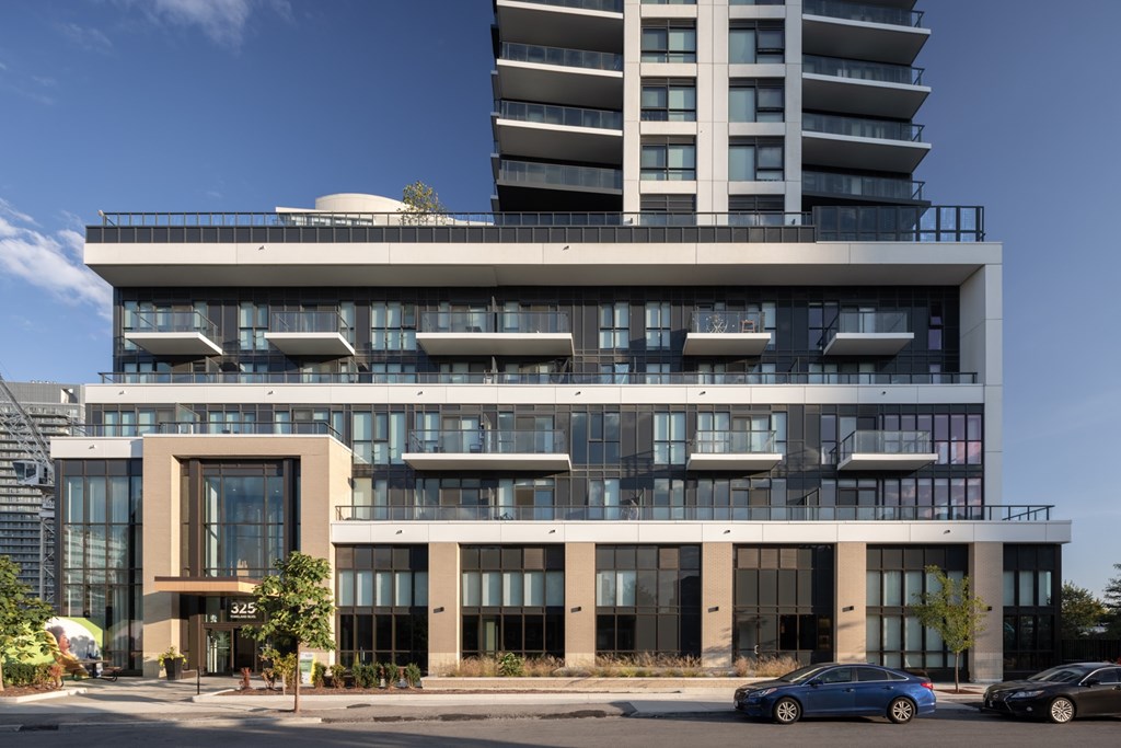 A modern building with a glass facade and a car parked in front.