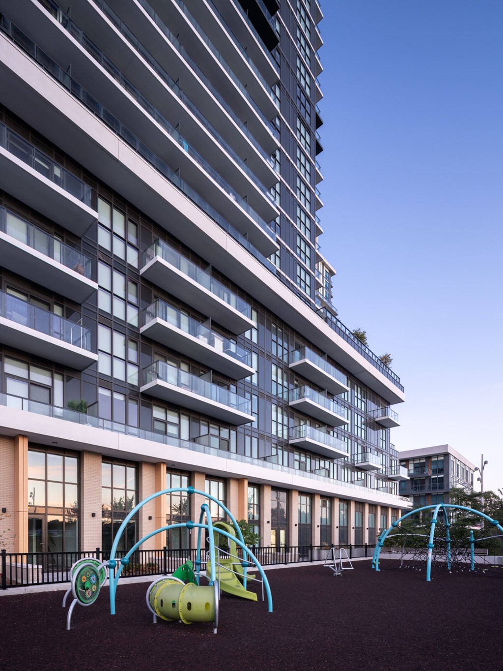 A playground with a slide and swings in front of a tall building.