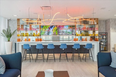 A modern bar with blue chairs and a white counter.